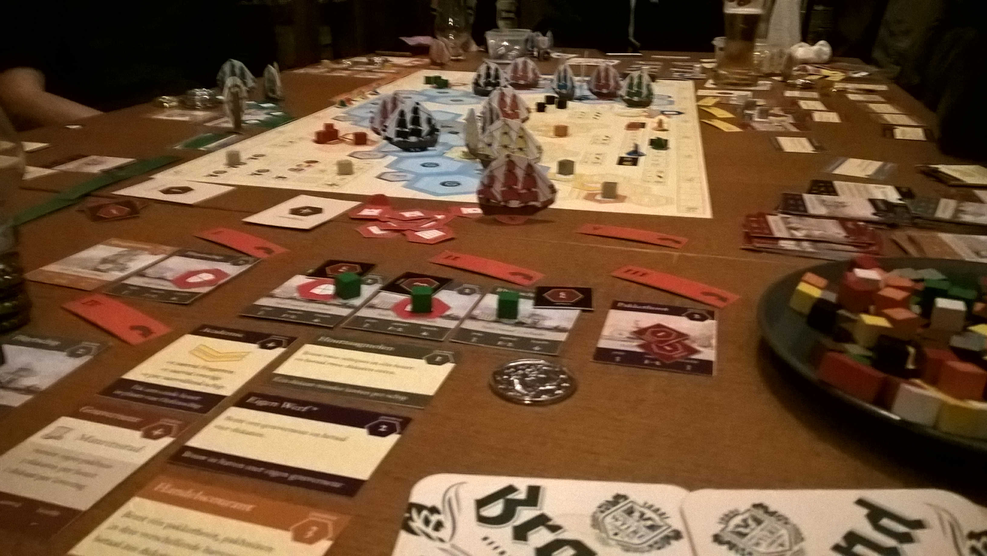 The full game board of the Admiralen board game in the middle of a play test session with card of both players at each side.